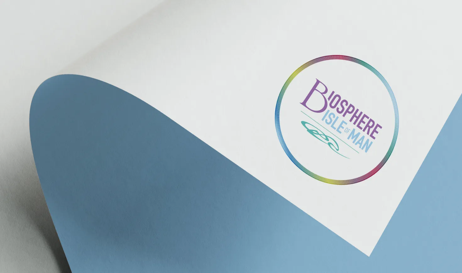 Biosphere Isle of Man logo printed on white paper, showing the circular rainbow ring mark with Celtic motif and the organisation name, designed by DotPerformance